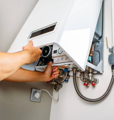 Plumber attaches Trying To Fix the Problem with the Residential Heating Equipment. Repair of a gas boiler